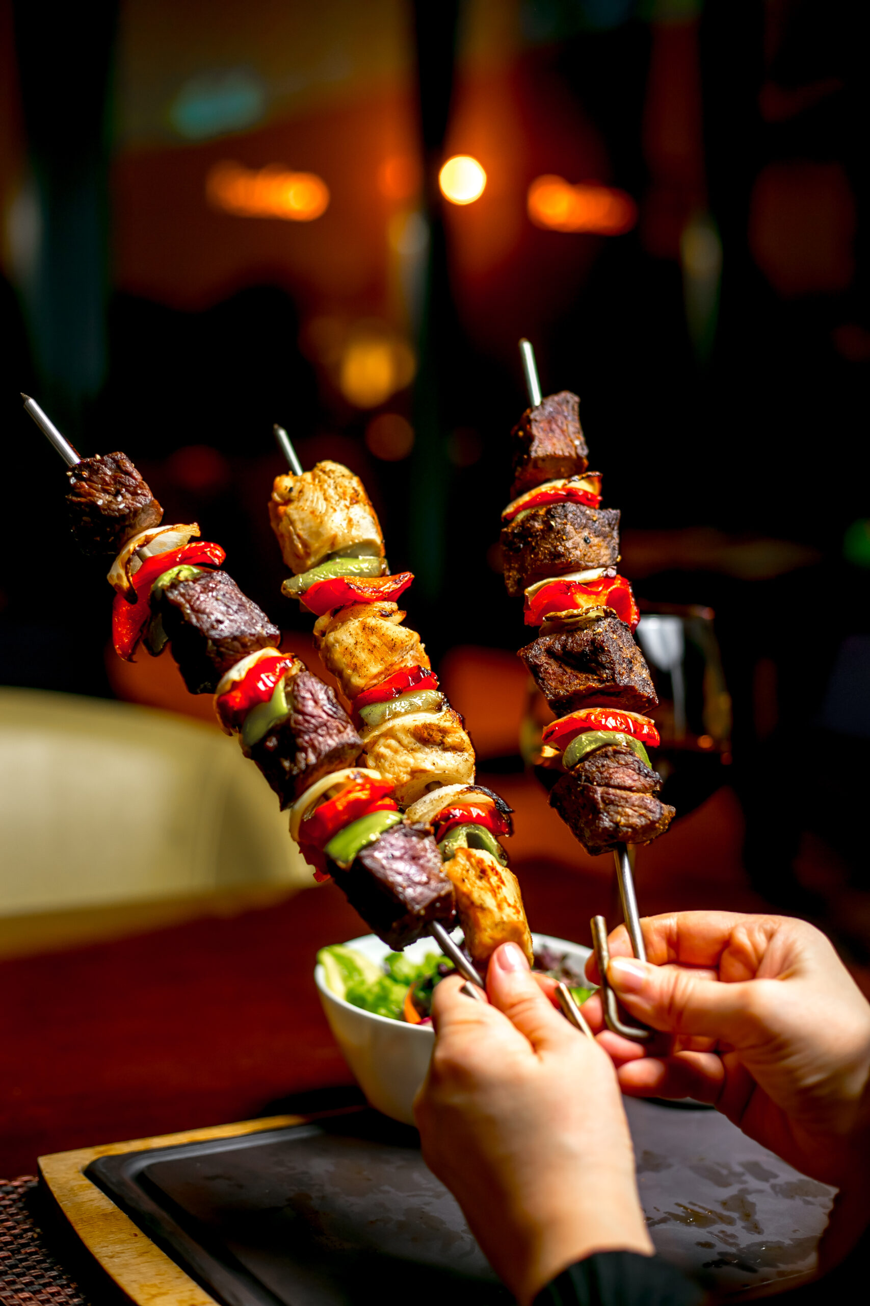 hands holding shish kebab with colorful bell peppers scaled